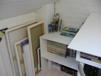 Studio shelves with art materials, books and work boards